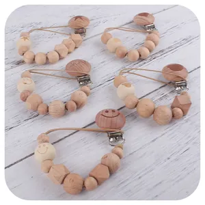 Natural beech wood pacifier clips with animal engravings and wooden beads on white wood