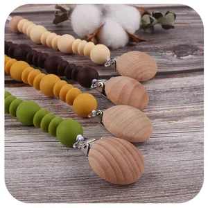 Silicone and beech wood baby pacifier clips in four natural colors on wood background