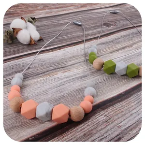 Baby teething necklace with silicone and wood beads on a dark wood background