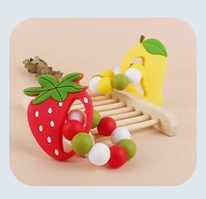 Vue détaillée d'un anneau de dentition en silicone forme fraise et mangue sur support bois