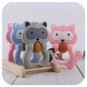 Cartoon raccoon silicone baby teether rings in pink blue and grey on wooden display