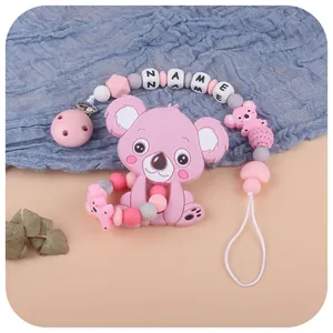 Pink silicone koala teether set with customizable name pacifier clip on blue fabric