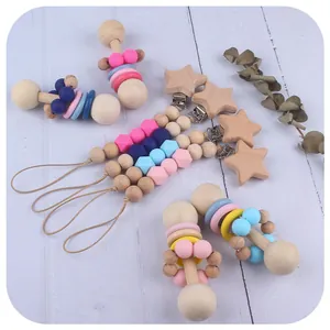 Set de sonajero de madera para bebés y sujetachupetes de silicona en fondo de madera natural