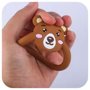 Jouet de dentition ours en silicone brun pressé pour montrer sa texture souple et douce