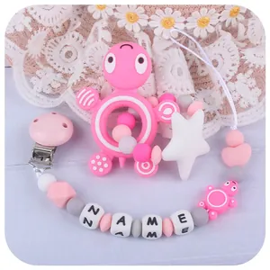 Pink turtle silicone teether and personalized pacifier clip set on wooden background