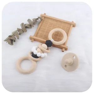 Hochet de dentition en bois pour bébé et tétine en silicone beige sur fond en peluche blanche