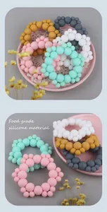 Food grade silicone baby teething rings in various colors on a decorative tray