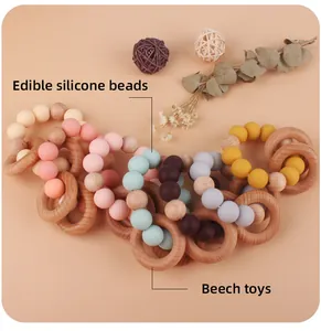 Close-up of beech wood and pastel silicone bead baby teething bracelets on soft background