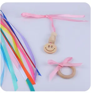 Détail d'un jouet sensoriel en bois pour bébé avec smiley et rubans colorés