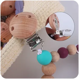Beech wood and silicone feather pacifier clip with colorful beads on a soft knit background
