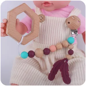 Beechwood pacifier clip with silicone feathers on a baby outfit mannequin