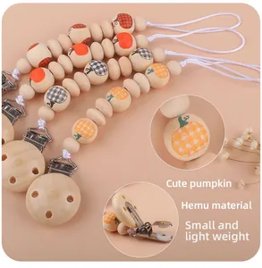 Detalle del sujetachupetes de madera con cuentas de calabaza y clips metálicos