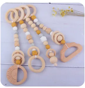 Detail of wooden beech baby teether with silicone beads and sun pendant on wood surface