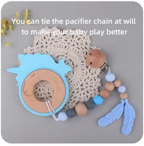 Close-up of baby teether set with blue unicorn silicone ring and wooden beaded pacifier clip