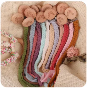 Flat lay of colorful braided cotton baby pacifier clips with rainbow engraved wooden clips