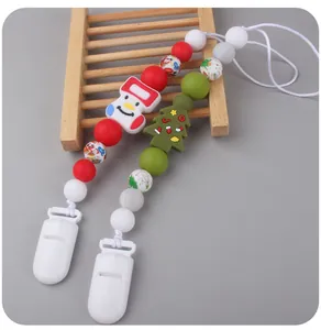 Close-up of silicone baby pacifier clips with festive snowman and Christmas tree charms