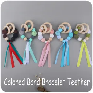 Detail view of colorful silicone teething bracelets with wooden rings and silk ribbons