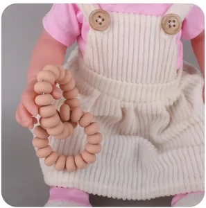 Detailed view of baby silicone teething rings held by doll for size reference