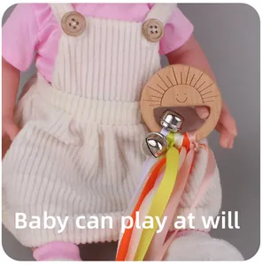 Detail of wooden baby teether rattle with sun engraving, bells and colorful ribbons