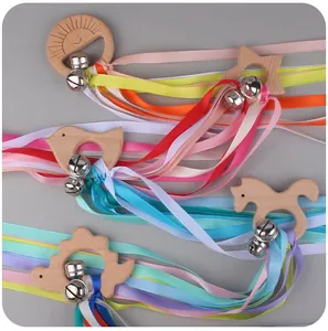 Macro detail of infant sensory wooden teether ring with colorful ribbons and silver bells