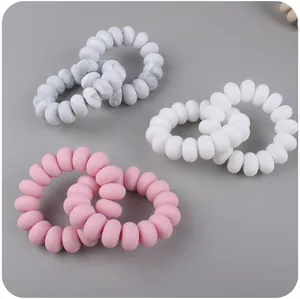 Macro shot of matte silicone spiral teether rings in grey, white, and pink sets