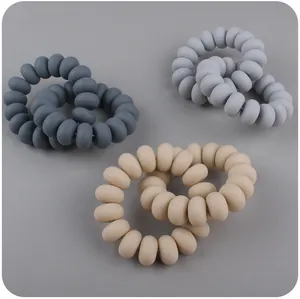 Macro view of multi-color spiral silicone baby teether rings in neutral Morandi tones