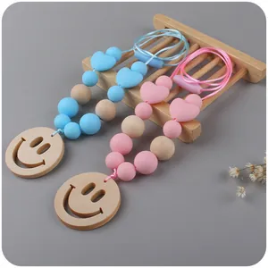 Detail of baby teething necklace with silicone beads and wooden smiley face pendant