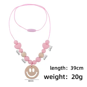 Baby teething necklace with pink silicone beads, wood beads and a smiley face wooden pendant