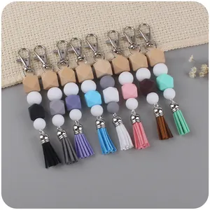 Nine colorful DIY silicone bead keychains with wood accents and suede tassels on fabric