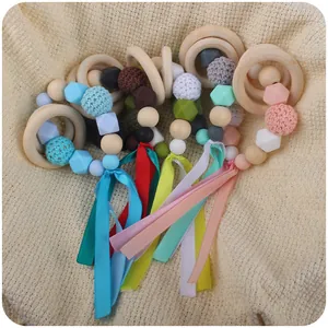 Silicone and wooden baby teething ring with colorful ribbons and crochet beads on knit mat