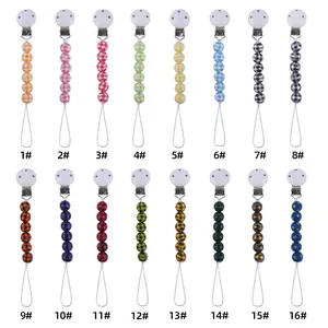 Macro display of 16 colorful baby pacifier clips featuring diverse plaid and star patterns