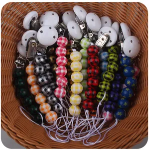 Close-up of baby pacifier clips with plaid beads and star patterns in a woven basket