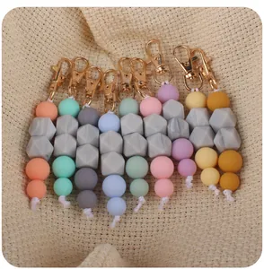 Detail of colorful silicone bead keychains with gold lobster clasps on textured fabric