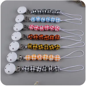 Detail of baby pacifier clips featuring multiple buffalo plaid beads and plastic clasps