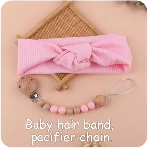 Detail of pink ribbed baby headband and wooden silicone pacifier chain set on tray