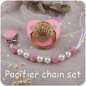 Detailed view of pink baby pacifier with gold crown emblem and matching pearl chain