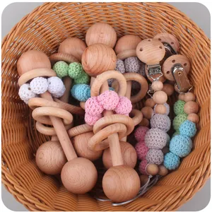Close-up of beech wood baby rattle and pacifier clip with crochet beads in a basket
