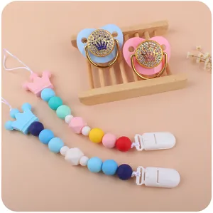Close-up of crown baby pacifiers with rhinestone accents and silicone beaded clips