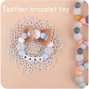 Close-up of baby teether bracelet with silicone beads and wooden rings on lace background