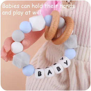 Baby teething toy with colorful silicone beads and natural wood rings held by a doll