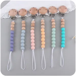 Silicone and beech wood pacifier clips in various macaron colors on neutral background