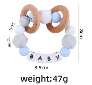 Detail of silicone teething bracelet with wood ring and letters spelling BABY