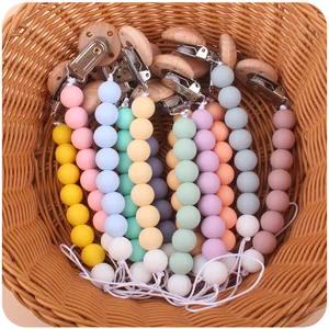 Catenelle per ciuccio con perline in silicone e clip in faggio in un cesto