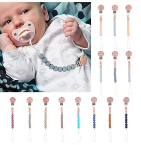 Detailed view of silicone pacifier clips in various Morandi colors with beech wood clamps