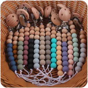 Detail of colorful food-grade silicone beads and beech wood pacifier clip set in basket