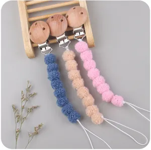 Detail of baby pacifier clip with wooden fastener and colorful knitted yarn balls
