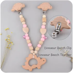 Close-up of pink silicone beads, wooden dinosaur teether and small bell for baby stroller