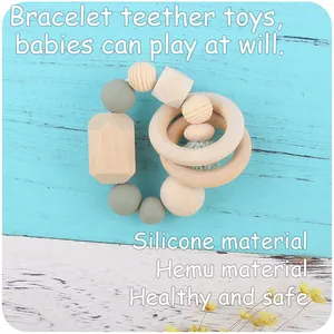 Detail of baby teething bracelet with beech wood beads and silicone rings on wooden surface