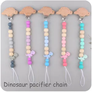 Detailed view of colorful silicone dinosaur pacifier clips with wood beads in five colors