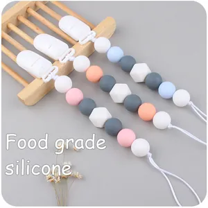 Detail of silicone pacifier clips with food-grade geometric beads on a wooden stand
